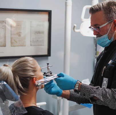 Image of dentist with blue gloves with blonde patient