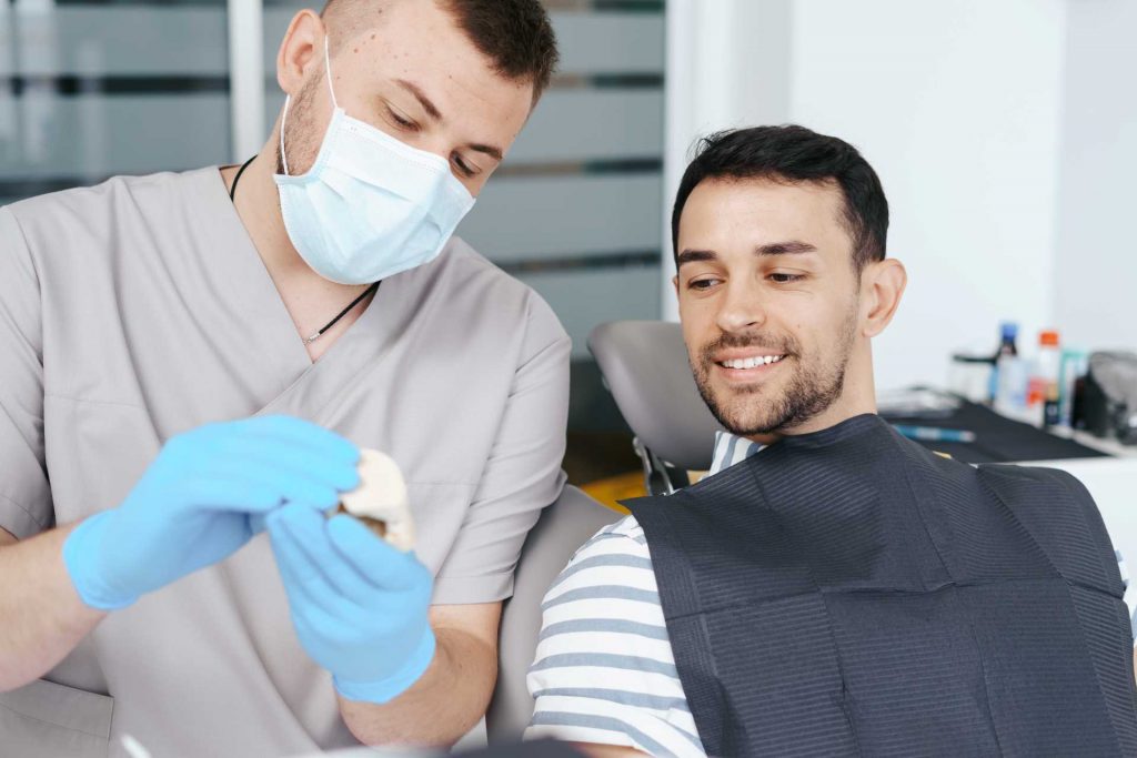 Male dentist showing patient a set of dentures | Featured image for learning to talk with dentures